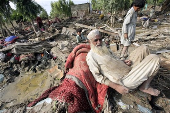 Pakistani villagers await aid Friday at their homes left in rubble by floods in Aza Kheil near Peshawar. International aid for Pakistani flood victims is coming in slowly compared to other recent disasters despite the massive number of people affected and the potential for dire economic consequences in a country key to Western hopes in the fight against Islamist extremists.